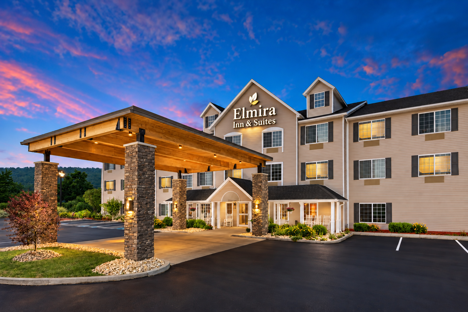 Elmira Inn and Suites illuminated exterior beneath a colorful evening sky